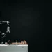An articulated robotic arm competes in chess on a board against a dark background, highlighting AI and innovation.