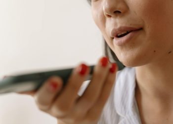 Close-up of a woman using smartphone voice command, showcasing technology and communication.