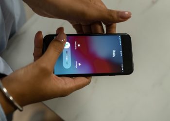Close-up image of hands holding a smartphone receiving a call from Ruby on a marble surface.