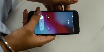 Close-up image of hands holding a smartphone receiving a call from Ruby on a marble surface.