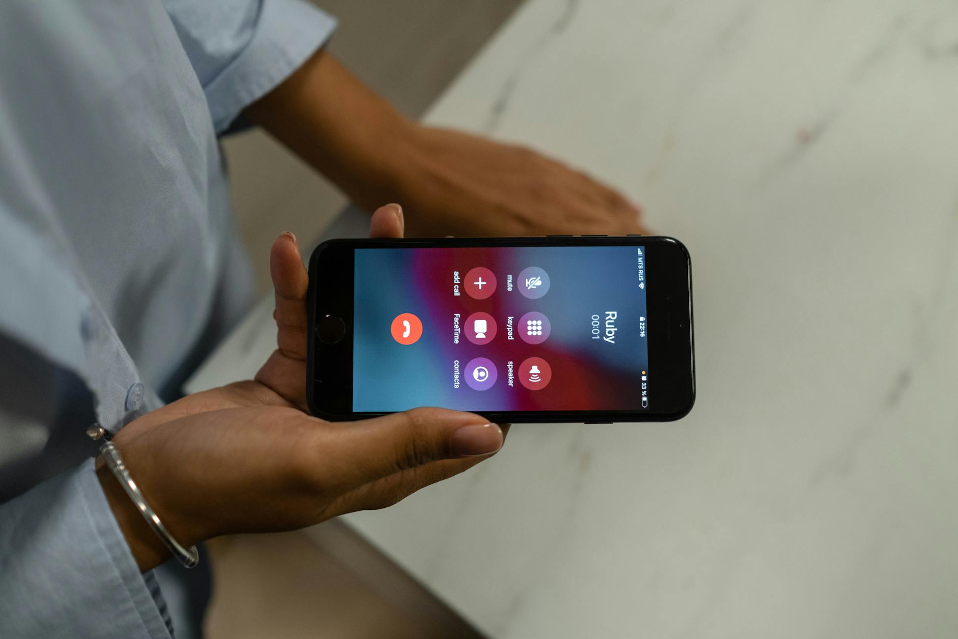 Close-up of a person holding a smartphone displaying an incoming call screen.