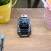 A small modern robot placed on a wooden desk surrounded by office supplies, showcases innovative technology.