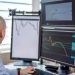 Trader analyzing financial data on multiple monitors in an office setting.