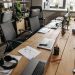 Spacious co-working office with wooden desks, laptops, and modern chairs.
