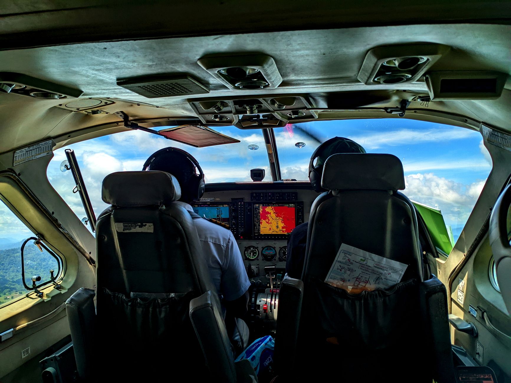 View from a small aircraft cockpit flying above the lush landscape of North Kalimantan, Indonesia.