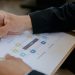 Close-up of a person writing on a business strategy document with a pen.