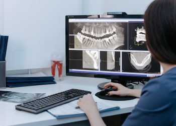 Dentist examining dental X-rays on a computer screen in a clinic.