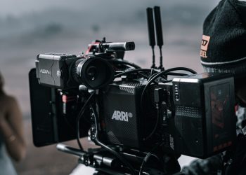 Close-up of a professional filmmaking camera setup on an outdoor set with blurred background.