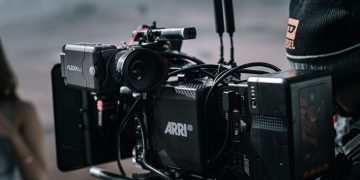 Close-up of a professional filmmaking camera setup on an outdoor set with blurred background.