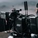 Close-up of a professional filmmaking camera setup on an outdoor set with blurred background.