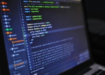 Close-up of a computer screen displaying programming code in a dark environment.