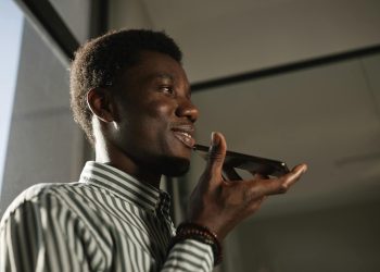 Smiling African American man talking on smartphone in an indoor setting.