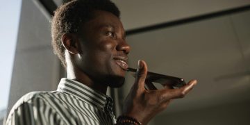 Smiling African American man talking on smartphone in an indoor setting.