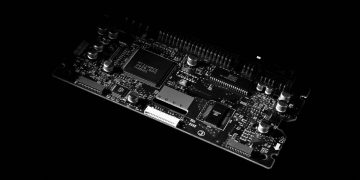 Detailed black and white image of a computer circuit board, showcasing technology components.
