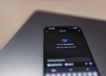 Close-up of a smartphone with AI assistant interface on screen over a laptop.