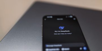 Close-up of a smartphone with AI assistant interface on screen over a laptop.