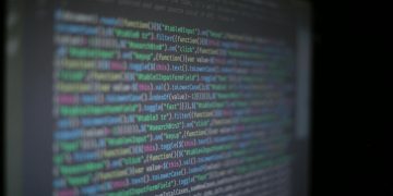 Close-up of colorful programming code on a blurred computer monitor.
