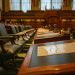 A detailed view of an empty legislative chamber with rows of desks and microphones, evoking governance.