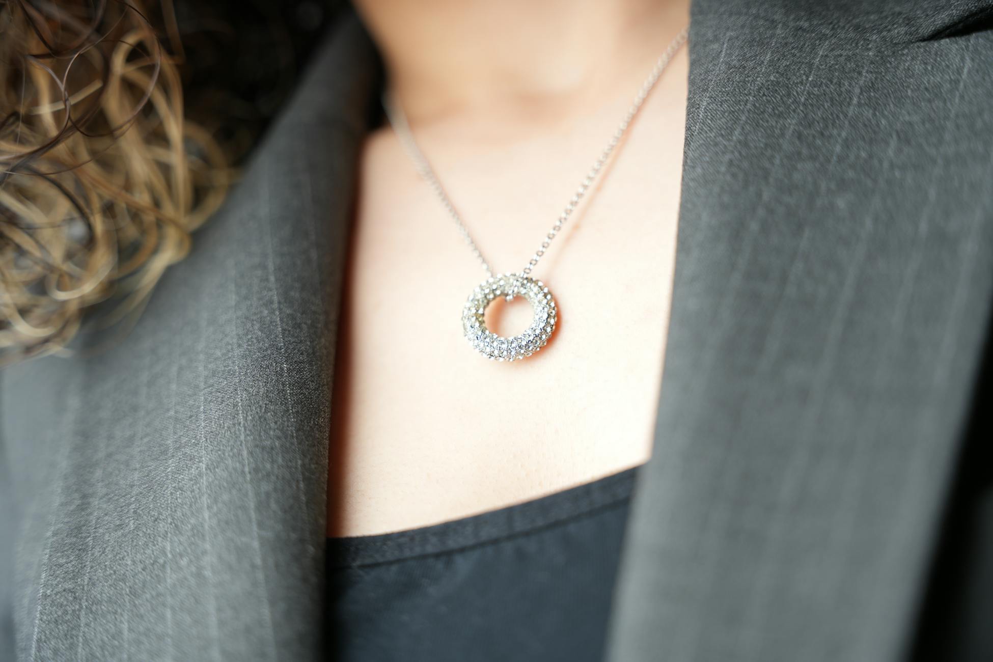 Close-up of a sparkling diamond pendant necklace against a business suit, showcasing elegance.
