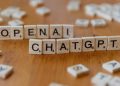 Wooden letter tiles spelling 'OPENAI CHATGPT' on a wooden surface, focused image.
