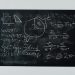 Detailed view of mathematical equations and diagrams on a blackboard.