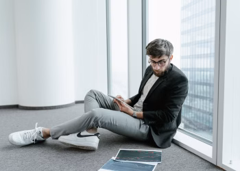 A man in an office setting using a tablet to analyze stock market data with graphs.