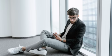 A man in an office setting using a tablet to analyze stock market data with graphs.