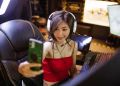 A young woman gamer with headphones taking a selfie during a gaming session.