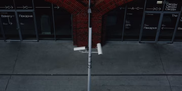 Street view with security cameras and an urban industrial building facade.