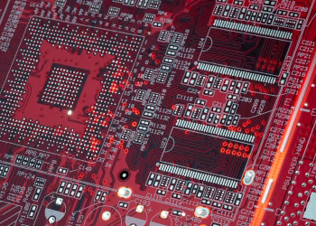 Detailed shot of a red motherboard showcasing electronic components and circuits.