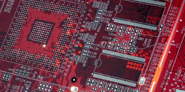 Detailed shot of a red motherboard showcasing electronic components and circuits.