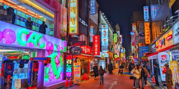 Explore the vibrant nightlife of Seoul's bustling street with colorful neon signs and lively atmosphere.