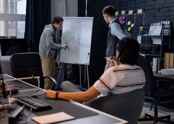 Business team in a modern office brainstorming ideas on a whiteboard. Engaged discussion and planning.