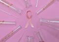 A pink ribbon surrounded by laboratory glassware symbolizes breast cancer research and awareness.