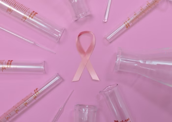 A pink ribbon surrounded by laboratory glassware symbolizes breast cancer research and awareness.