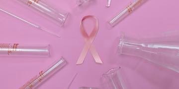 A pink ribbon surrounded by laboratory glassware symbolizes breast cancer research and awareness.