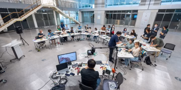 Wide shot of students in a modern university classroom engaging with technology and learning.