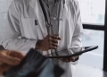 A professional medical practitioner holding a tablet, focused on work in a clinical setting.