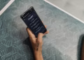 Close-up of a person holding a smartphone displaying the ChatGPT application interface on a patterned table.
