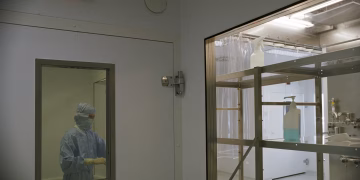 Image of a cleanroom in a medical facility featuring sterile equipment and a person in protective clothing.