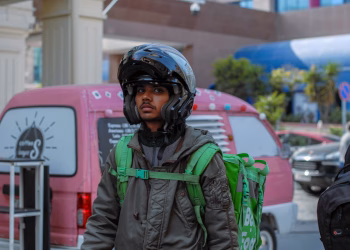 Courier on city streets with helmet and backpack, ready for delivery tasks.