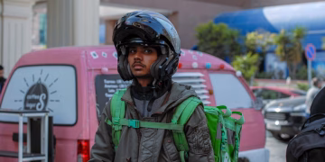 Courier on city streets with helmet and backpack, ready for delivery tasks.