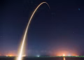Spectacular long exposure of a rocket launch under a clear, starry night sky showcasing the trail.