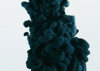 Close-up of dark ink swirling in water against a white backdrop, showcasing abstract art.