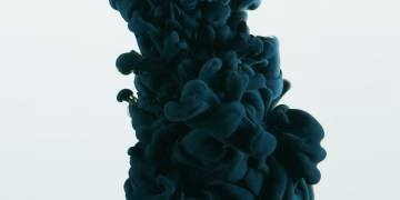 Close-up of dark ink swirling in water against a white backdrop, showcasing abstract art.