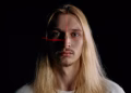 Close-up portrait of a man under laser scanning in low light, showcasing modern facial recognition technology.