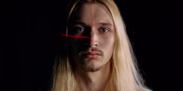 Close-up portrait of a man under laser scanning in low light, showcasing modern facial recognition technology.