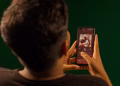 A person using a smartphone to stream music from a streaming service app indoors.