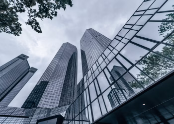 Modern skyscrapers with glass facades reflecting the urban skyline on an overcast day.