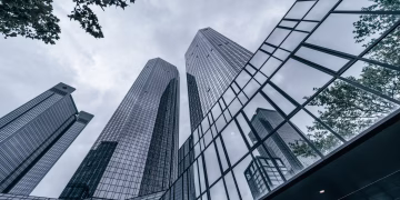 Modern skyscrapers with glass facades reflecting the urban skyline on an overcast day.